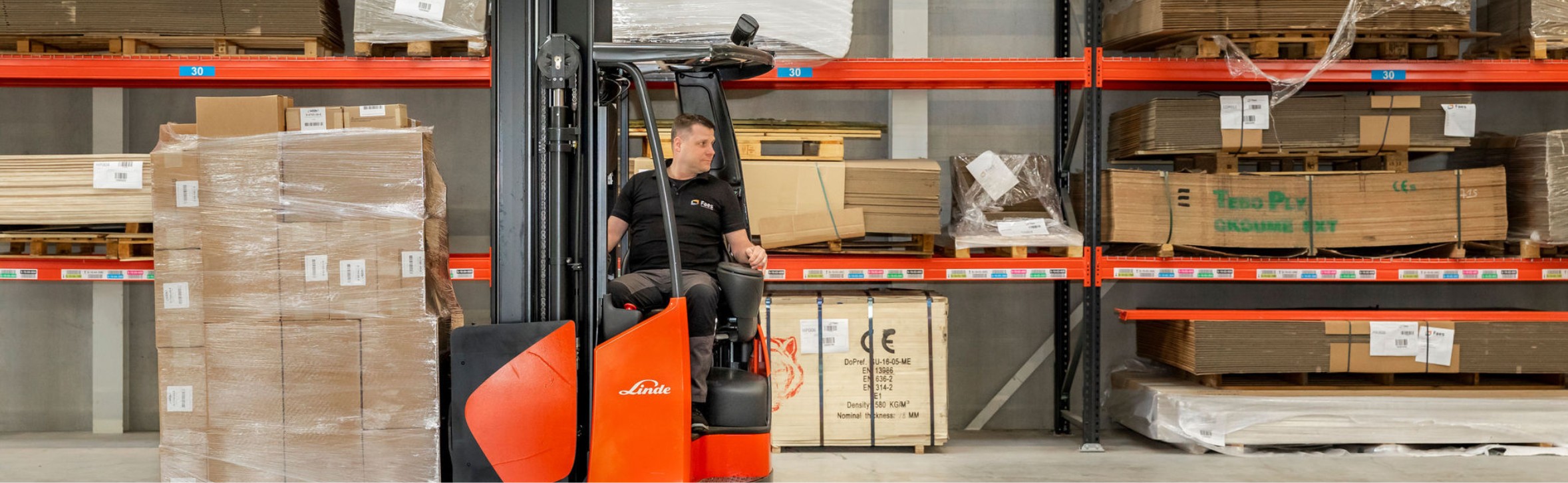 Faes medewerker in magazijn met heftruck verplaatst pallets en karton