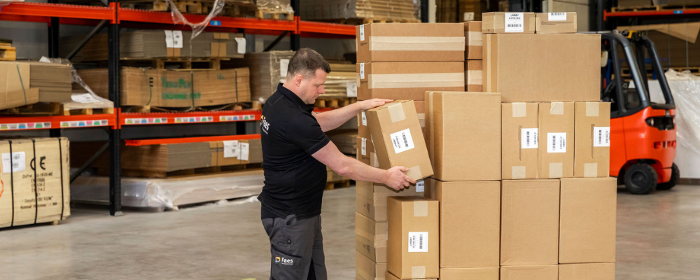 Een medewerker van Faes stapelt zorgvuldig dozen op een pallet, gebruikmakend van StackAssist voor een optimale belading van zijn transport.