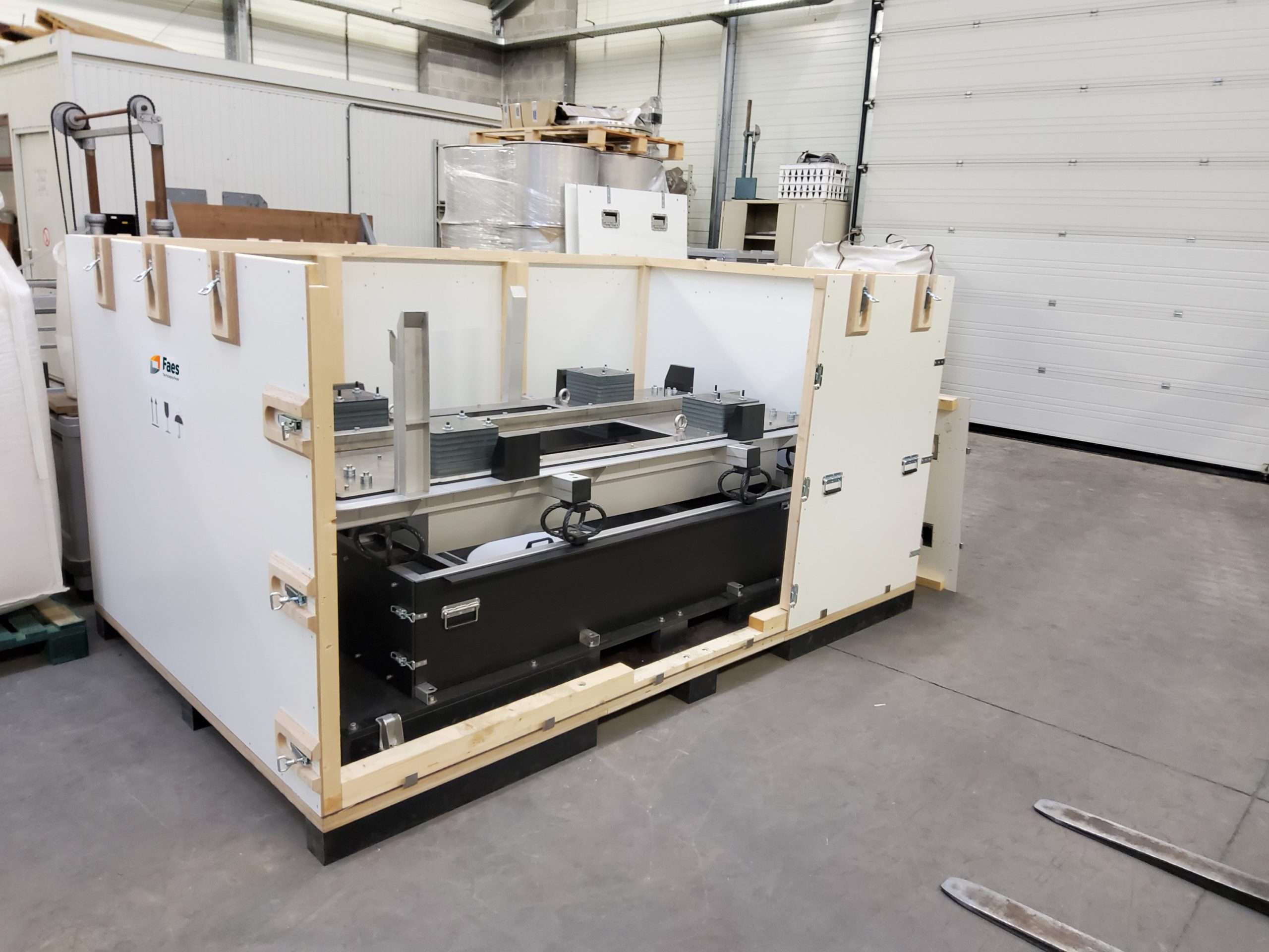 Open houten maatwerk kist van Faes met veilige bevestiging van industriële apparatuur. De kist is ontworpen voor transport en opslag van gevoelige technische componenten, met stevige metalen sluitingen en intern schuim voor bescherming. Ideaal voor export van waardevolle industriële goederen.
