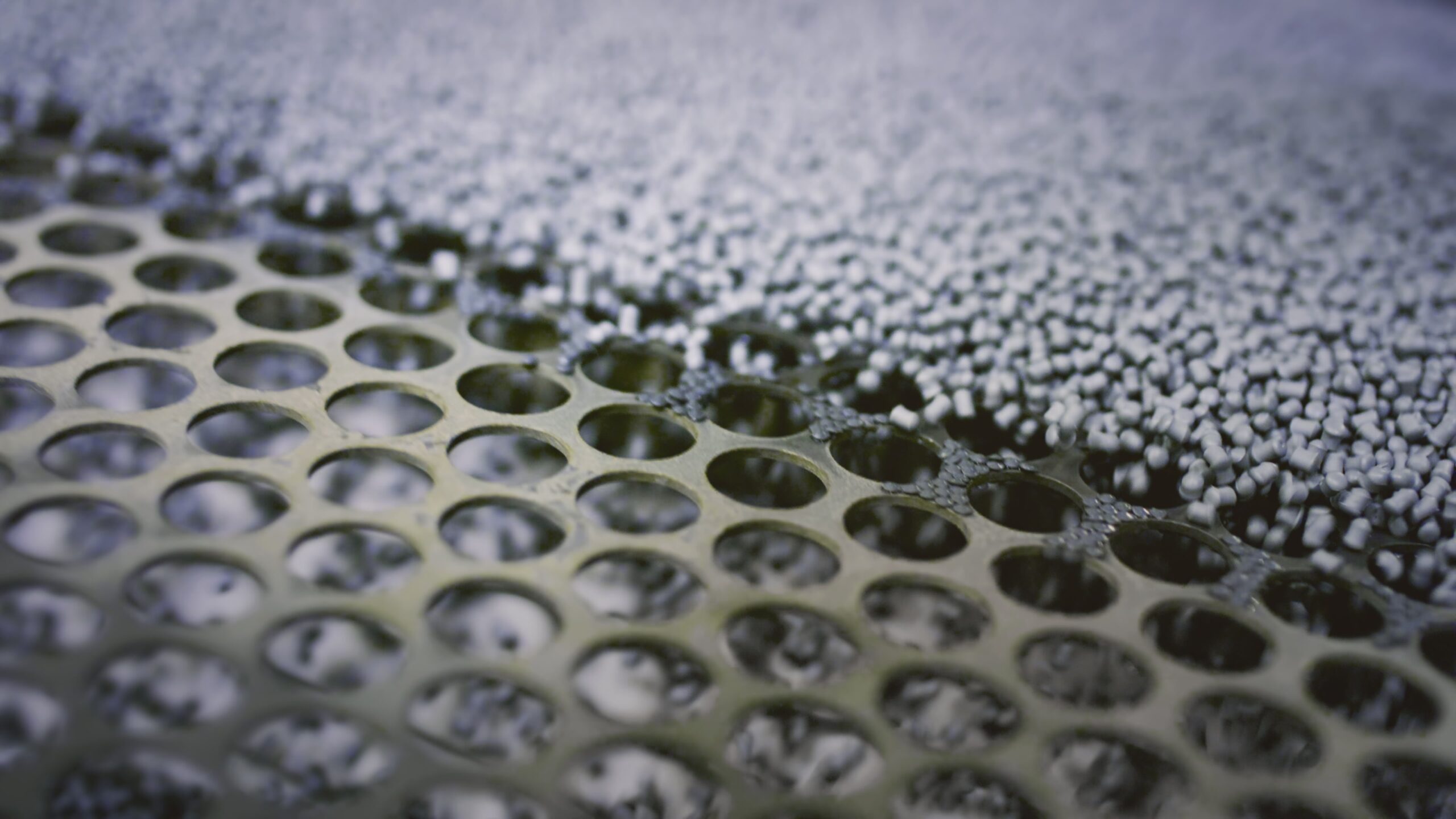 Close-up van kunststofkorrels op industriële zeef tijdens materiaalverwerking